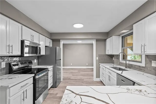 a kitchen with stainless steel appliances kitchen island granite countertop a sink stove and refrigerator