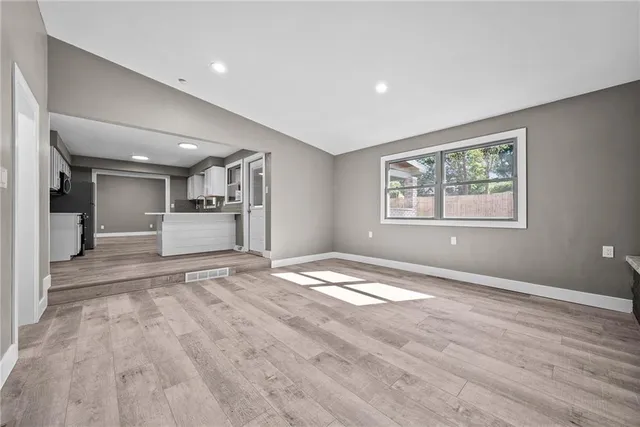a view of empty room with wooden floor and window