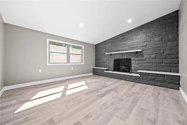 an empty room with windows and fireplace