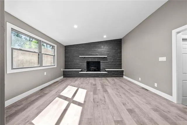 wooden floor fireplace and windows in an empty room