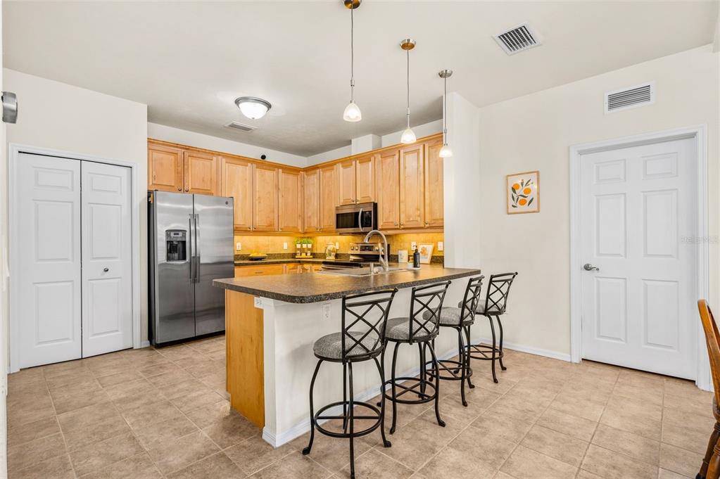 11550 Northwest 17 Place Gainesville, FL 32606 - Photo 8 of 48 a kitchen with stainless steel appliances granite countertop a stove a refrigerator a oven a sink with island chairs and wooden cabinets