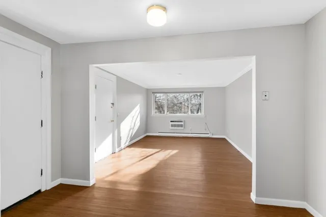 a view of an empty room with wooden floor and a window