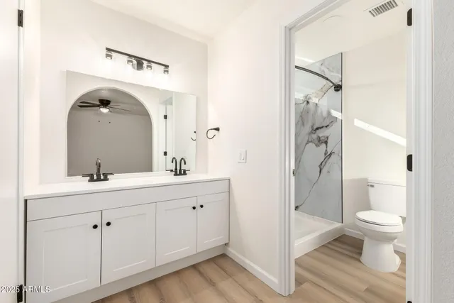 a en suite bathroom with a granite countertop sink toilet and shower glass cabinet