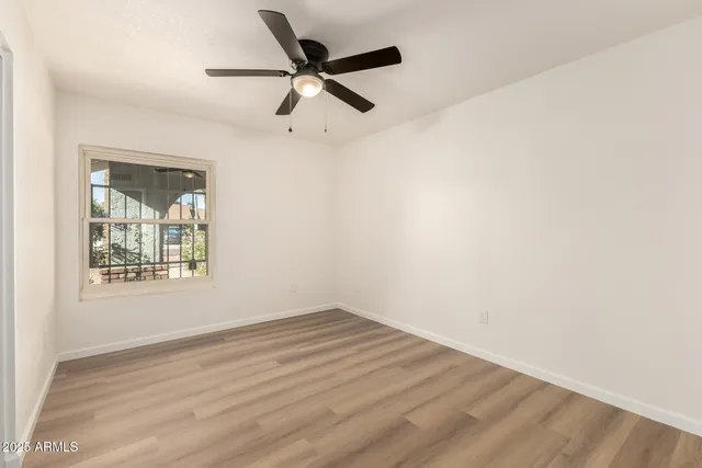 an empty room with wooden floor fan and windows