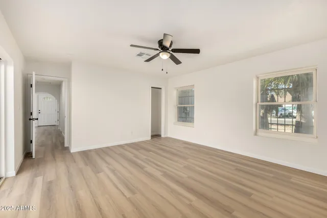 a view of empty room with wooden floor and fan