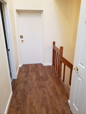 a view of a hallway with wooden floor and stairs