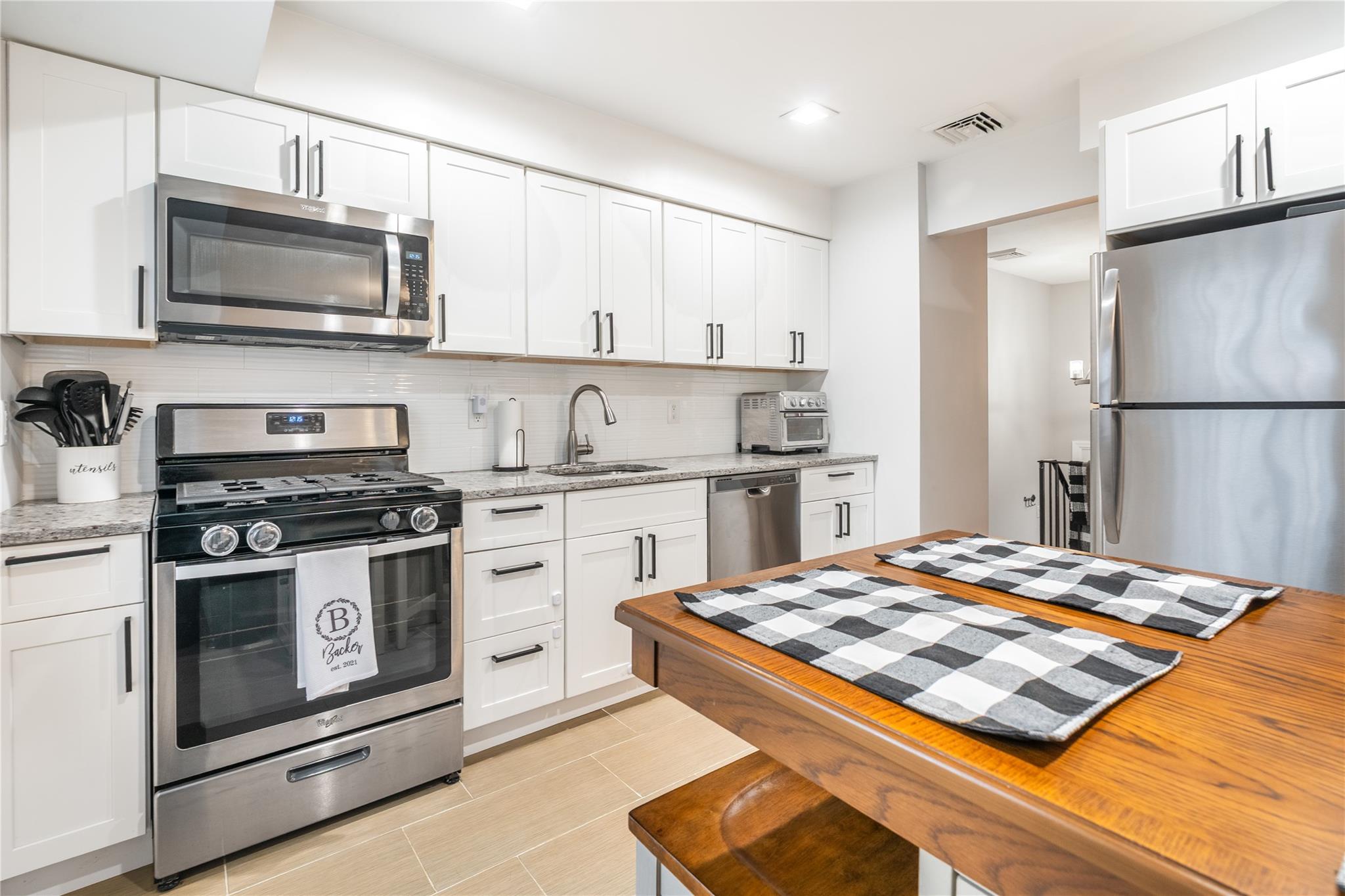 45 Raker Road Poughkeepsie, NY 12603 - Photo 9 of 25 Kitchen featuring backsplash, a sink, white cabinetry, stainless steel appliances, and visible vents