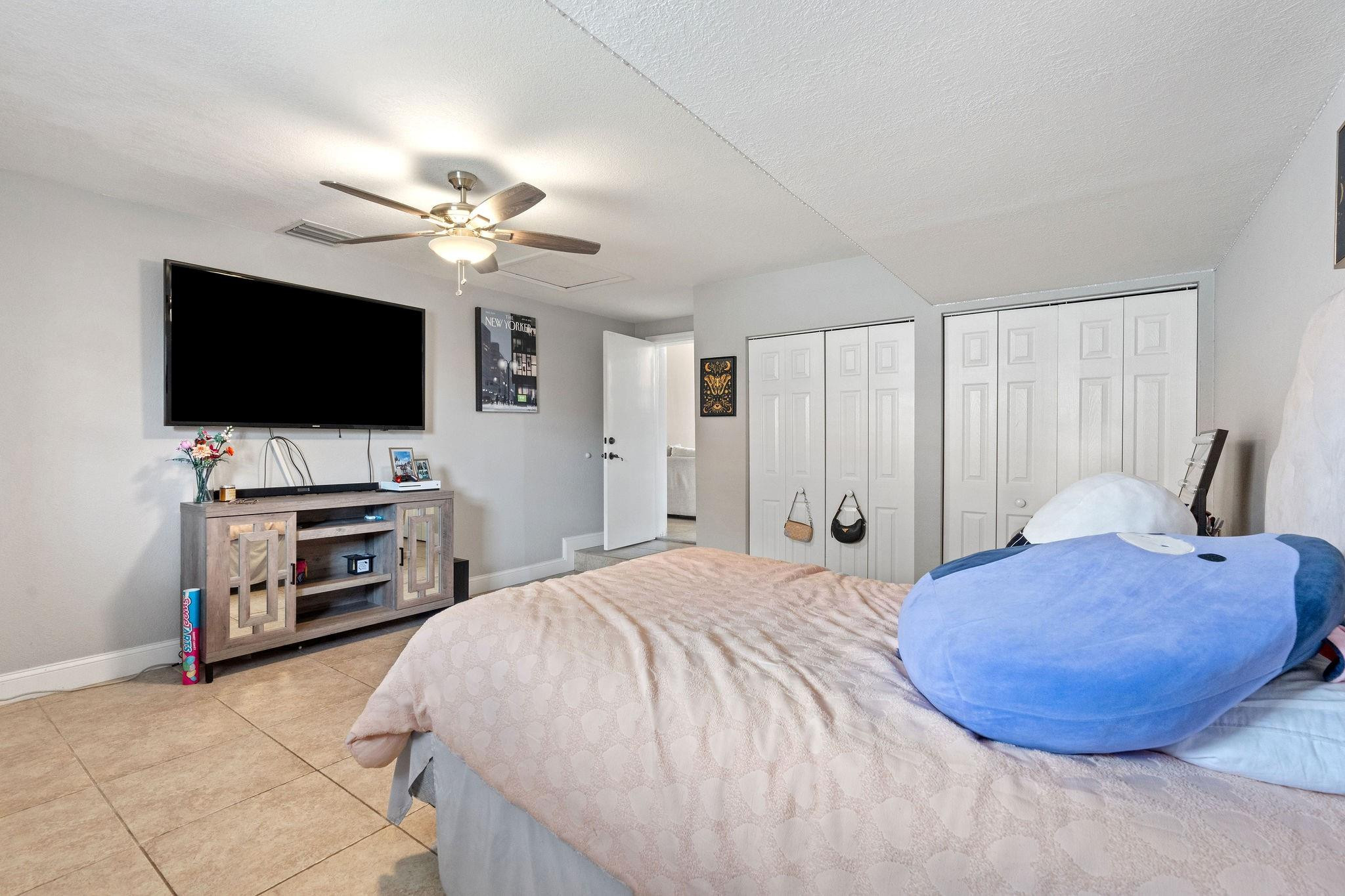 8313 Northwest 188th Terrace Hialeah, FL 33015 - Photo 34 of 50 a spacious bedroom with a bed and a flat screen tv