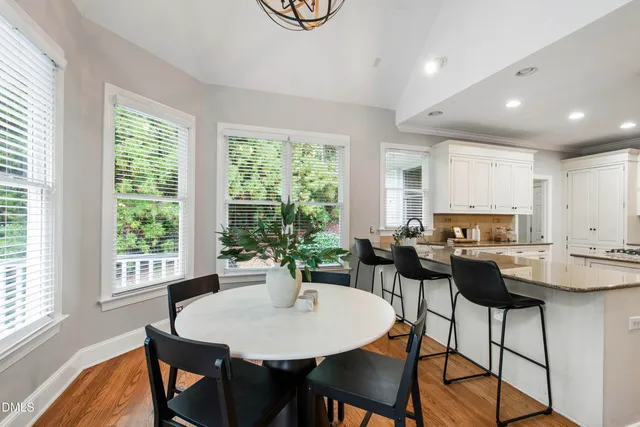 a kitchen with stainless steel appliances a stove a sink a refrigerator white cabinets and wooden floor next to a window