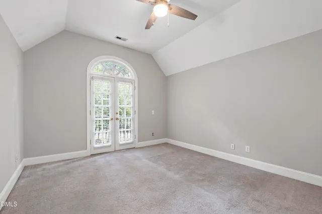 an empty room with wooden floor ceiling fan and windows