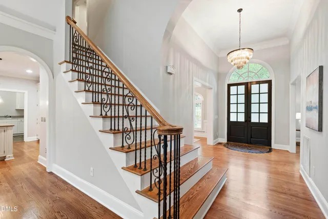 a open kitchen with stainless steel appliances granite countertop a stove top oven a refrigerator a sink and white cabinets with wooden floor