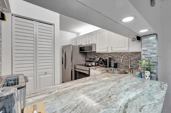 a kitchen with stainless steel appliances granite countertop a refrigerator sink stove microwave and cabinets