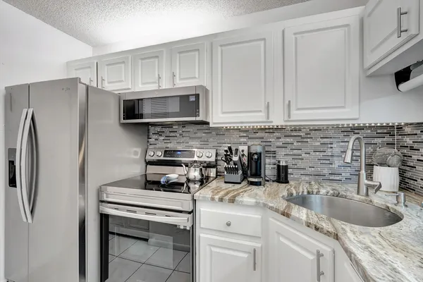 a kitchen with granite countertop a sink stove and refrigerator