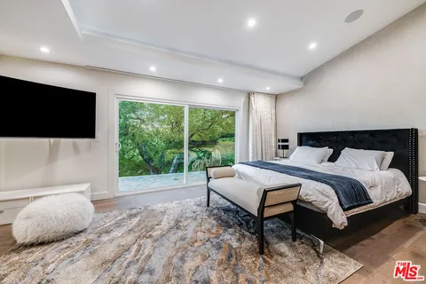 a large bed sitting in a spacious bedroom next to a flat tv screen and a dresser