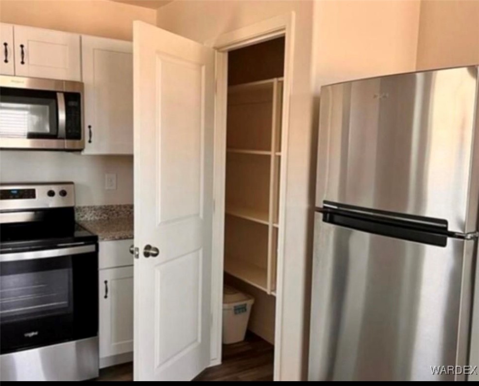 3665 East Koval Road Kingman, AZ 86409 - Photo 6 of 10 The kitchen features stainless steel appliances, white cabinetry with dark hardware, and a pantry with built-in shelving