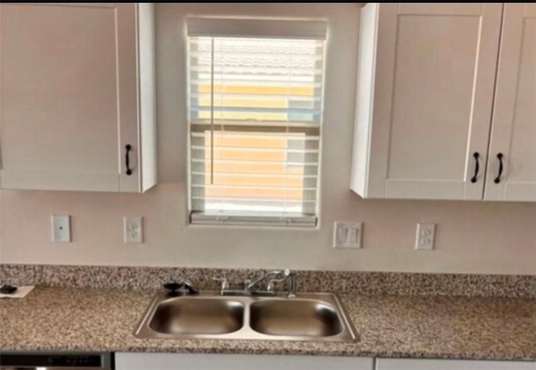 3665 East Koval Road Kingman, AZ 86409 - Photo 7 of 10 This kitchen features white cabinetry with dark hardware, a dual basin stainless steel sink with a chrome faucet, and a speckled countertop