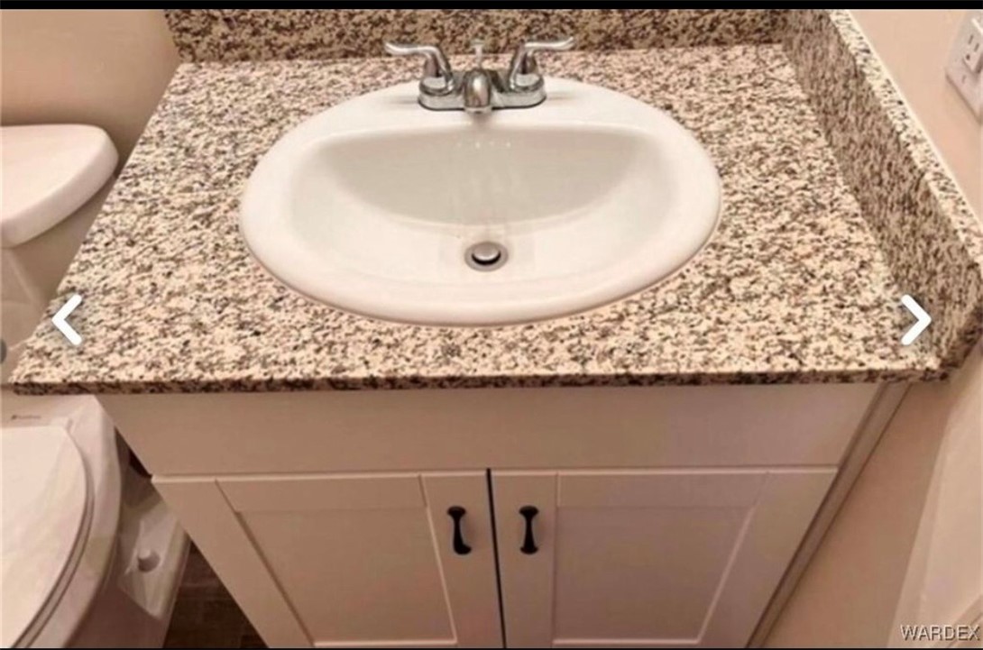 3665 East Koval Road Kingman, AZ 86409 - Photo 10 of 10 Bathroom vanity featuring a speckled granite countertop, an integrated white sink, and a chrome faucet