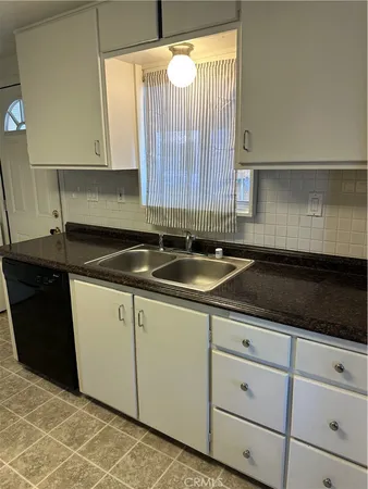 a kitchen with granite countertop a sink and a white cabinets