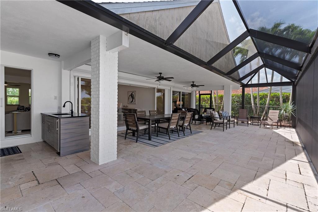 2500 Kings Lake Boulevard Naples, FL 34112 - Photo 22 of 31 a view of a patio with table and chairs potted plants with wooden fence