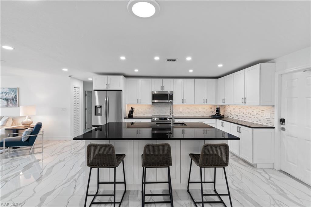 2500 Kings Lake Boulevard Naples, FL 34112 - Photo 7 of 31 a kitchen with stainless steel appliances kitchen island granite countertop a sink and cabinets