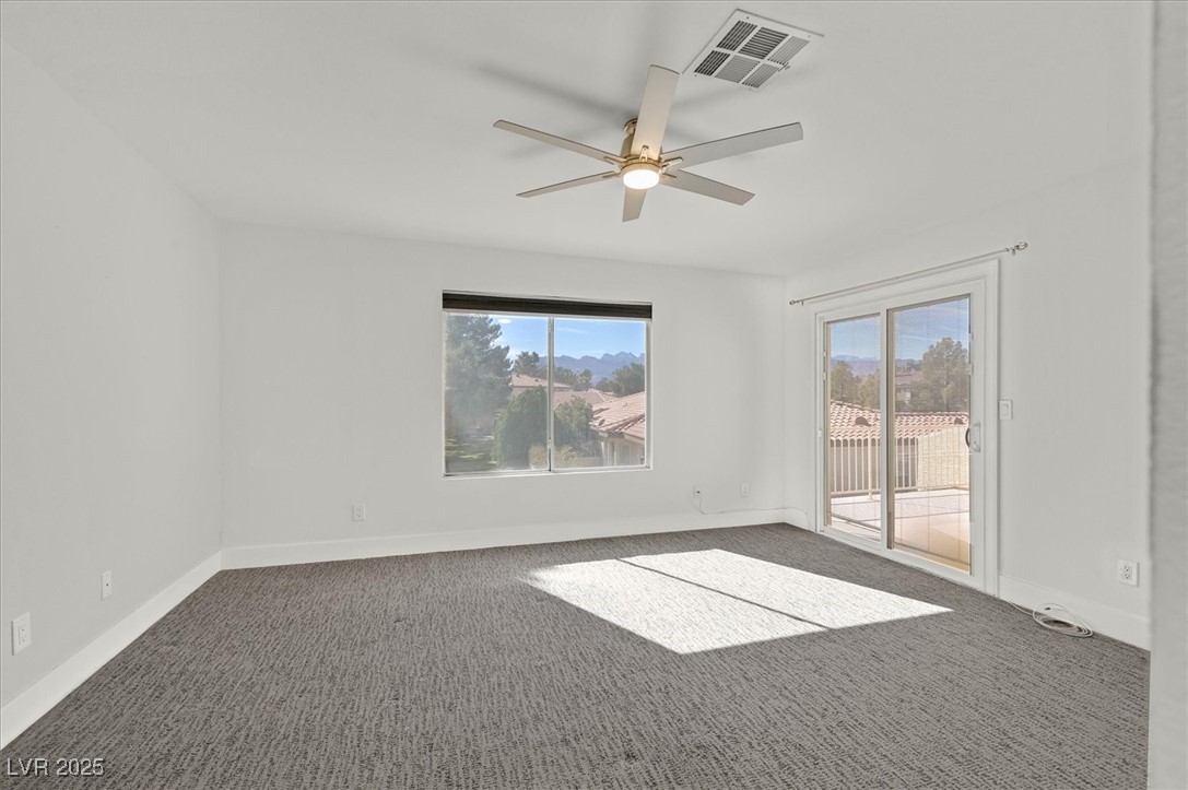 5421 Painted Mirage Road Las Vegas, NV 89149 - Photo 16 of 35 Empty room featuring dark colored carpet, visible vents, plenty of natural light, and baseboards