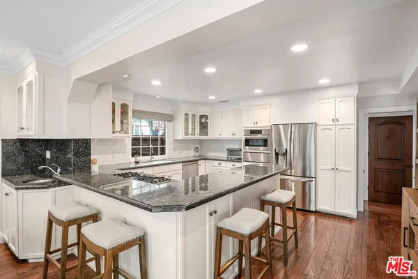 a kitchen with stainless steel appliances granite countertop a table chairs sink refrigerator and cabinets