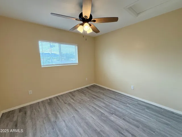 a view of an empty room with wooden floor and a chandelier fan