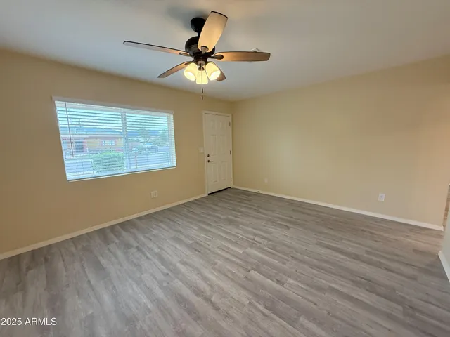 an empty room with wooden floor fan and windows