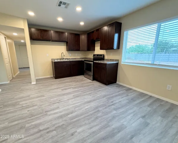 a kitchen with kitchen island granite countertop a sink and a stove top oven
