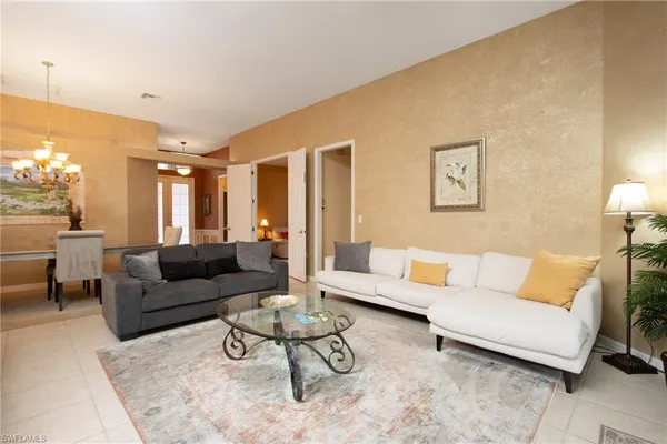 a living room with furniture and a large mirror next to a window