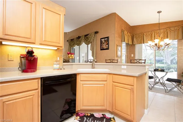 a kitchen with stainless steel appliances granite countertop a sink a stove top oven a chimney cabinets and a dining table