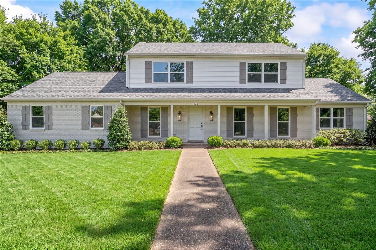 1676 Miller Farms Road Germantown, TN 38138 - Photo 2 of 37 Two-story residence featuring a white brick and siding exterior, dark gray shingle roof, and a covered porch with white columns