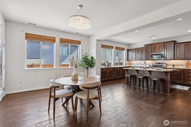 a room with stainless steel appliances kitchen island granite countertop furniture and a dining table with wooden floor