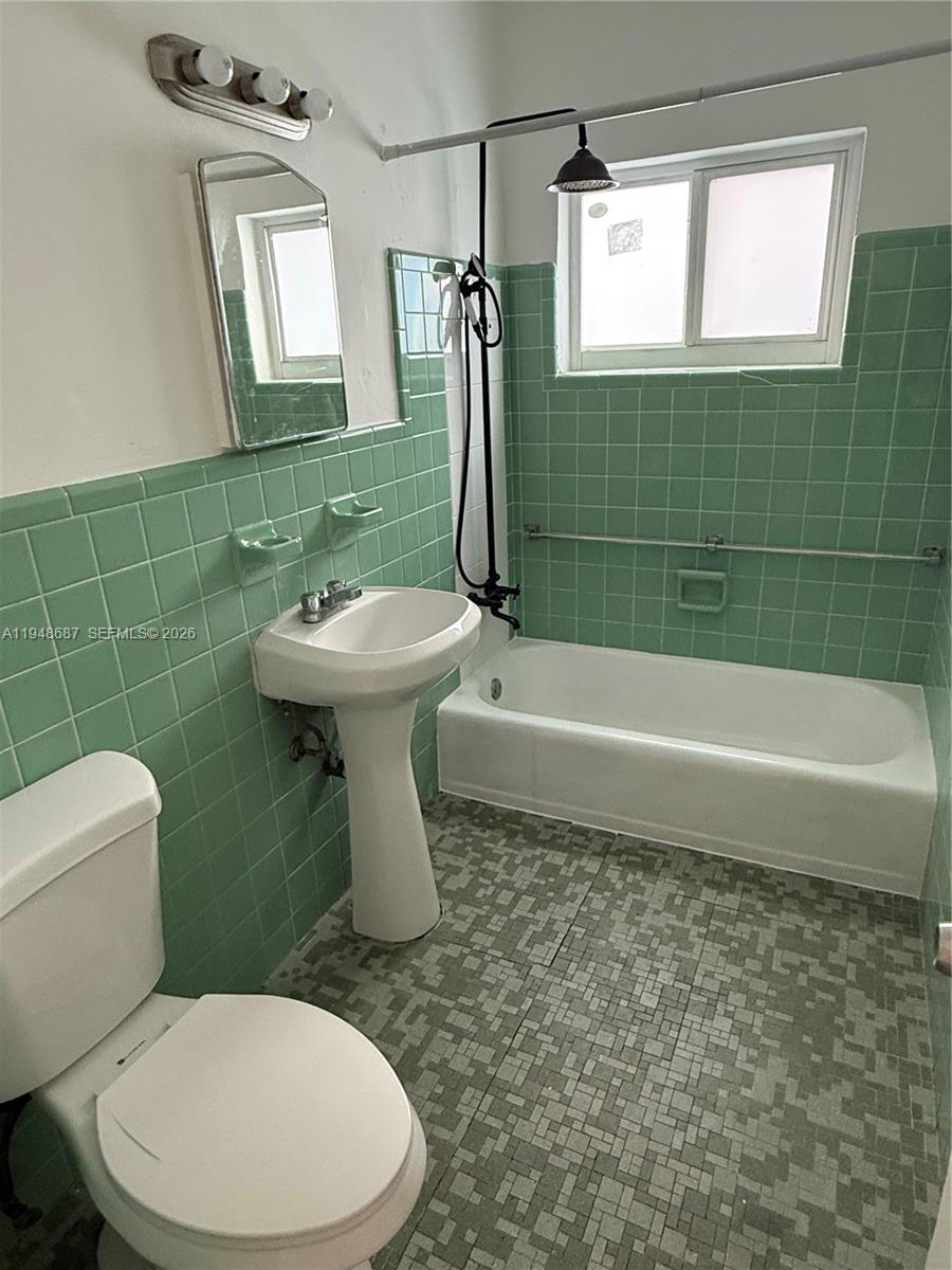 520 Northeast 82nd Terrace, Unit 10 Miami, FL 33138 - Photo 8 of 11 a bathroom with a toilet a sink and mirror