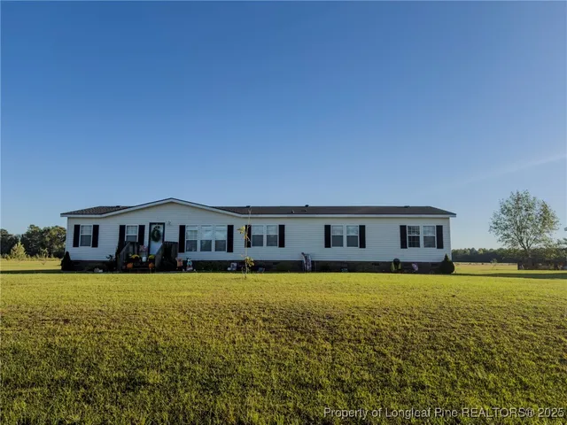 a view of a large pool with lawn chairs and large trees