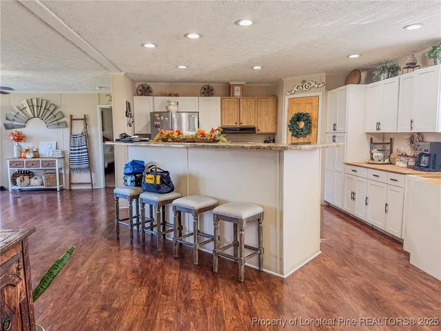a kitchen with stainless steel appliances granite countertop a dining table chairs microwave and cabinets