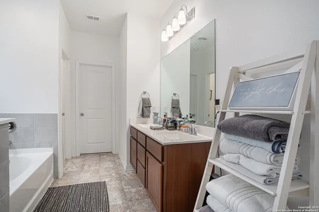 a en suite bathroom with a double vanity sink a mirror and a bathtub