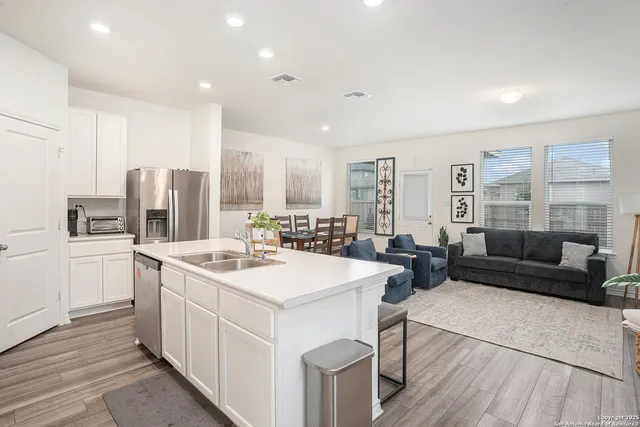 a view of a kitchen counter top space a sink wooden floor and living room view