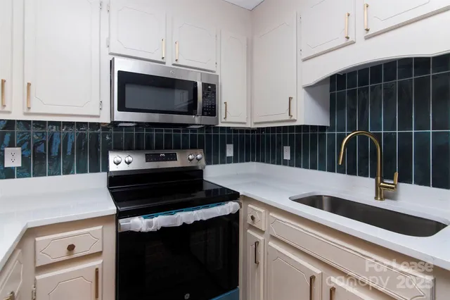a kitchen with a sink and a stove top oven with wooden floor