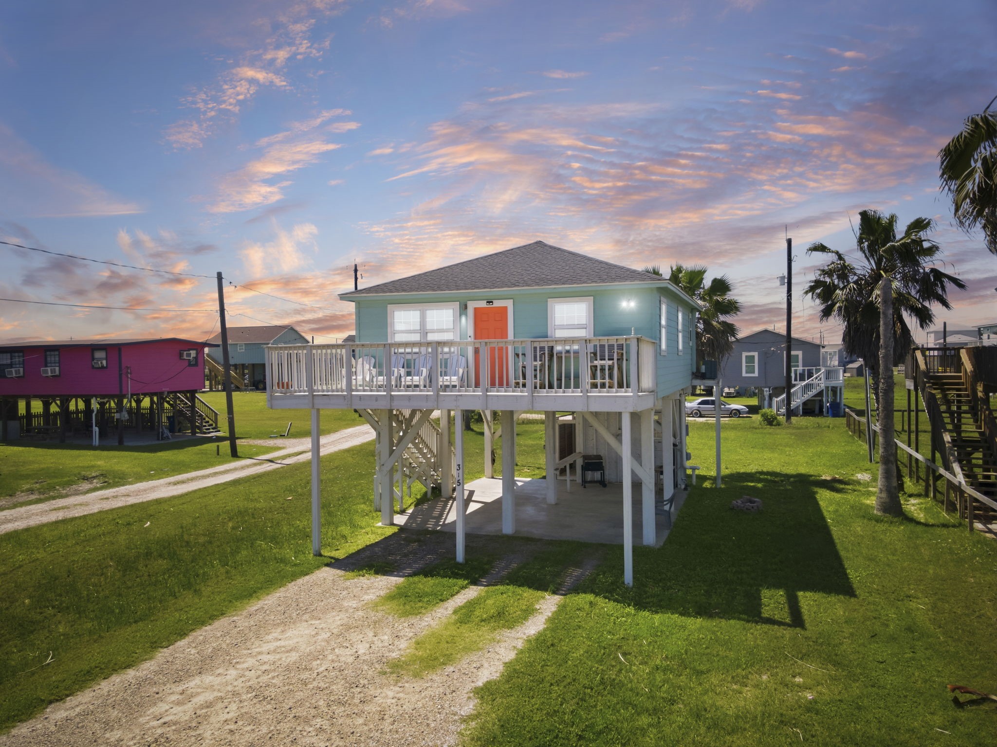 315 Caisson Street Surfside Beach, TX 77541 - Photo 27 of 32 Exterior / Front Elevation (Sunset) – Elevated home showcased in warm sunset light, highlighting the inviting front deck and raised construction design.