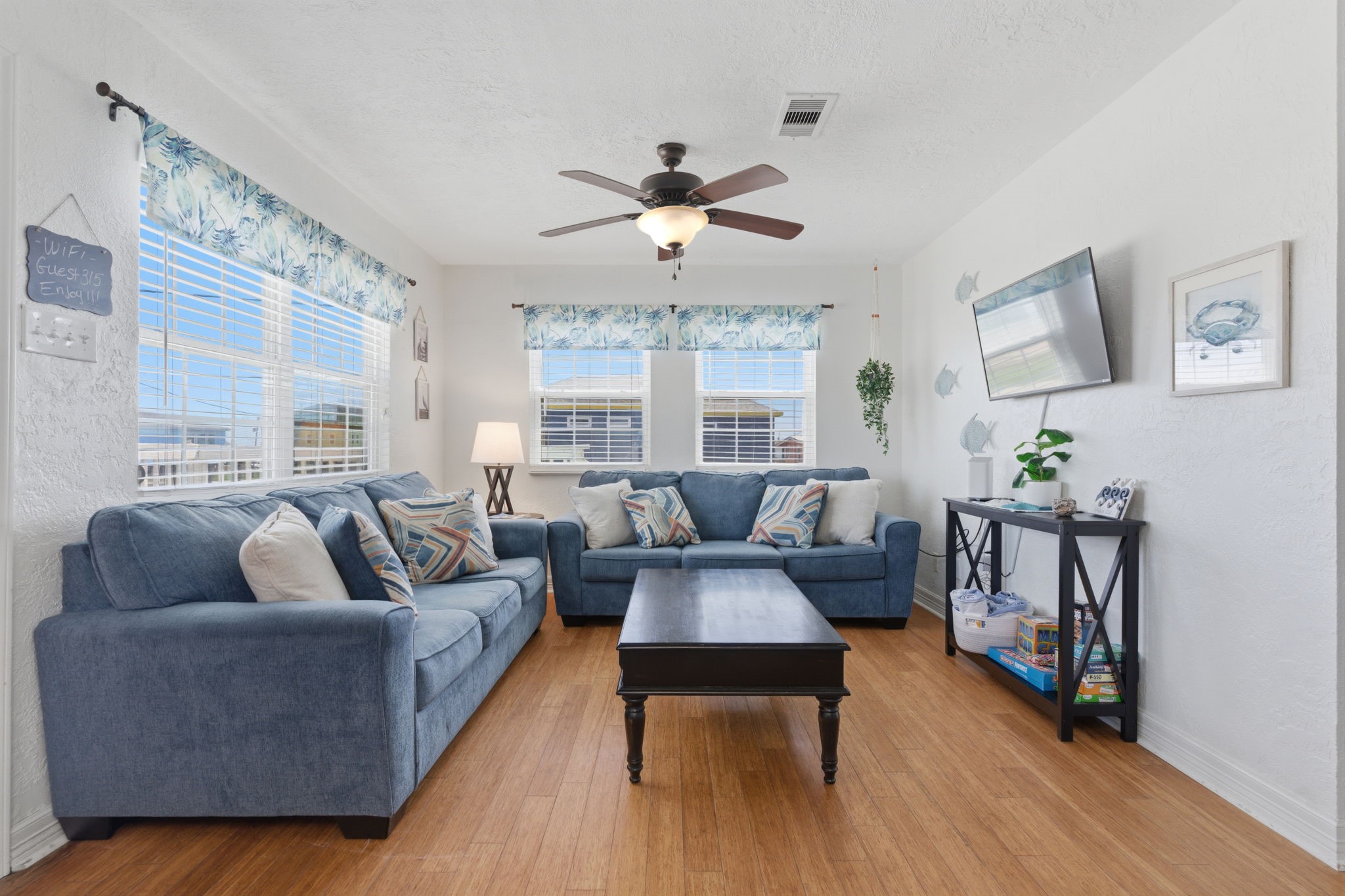 315 Caisson Street Surfside Beach, TX 77541 - Photo 3 of 32 Living Room – Bright and inviting living area with wood-look flooring, abundant natural light, and a comfortable seating arrangement—ideal for relaxing or entertaining.