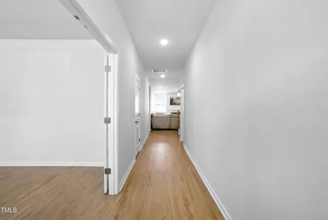 a view of a hallway with wooden floor and a bathroom