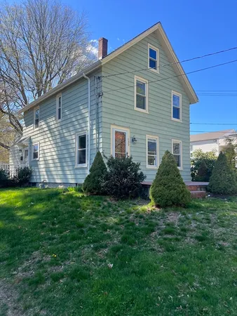 a view of a house with a yard plants and large tree