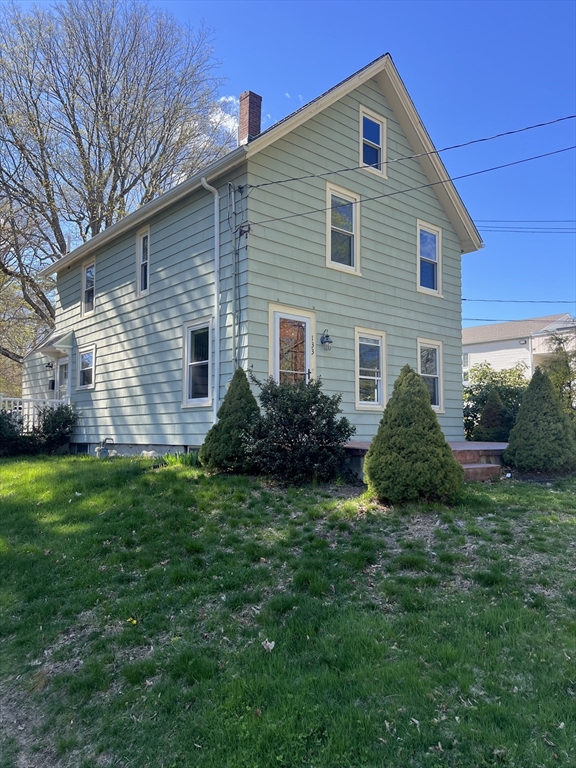 a view of a house with a yard plants and large tree