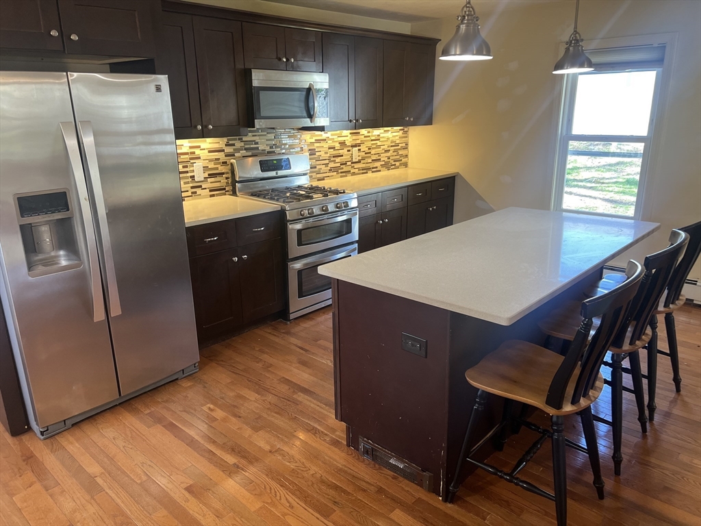 133 Pond Street Sharon, MA 02067 - Photo 5 of 17 a kitchen with stainless steel appliances a table chairs and a refrigerator