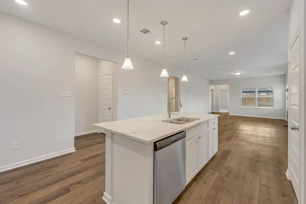 a kitchen with a stove a sink a refrigerator and white cabinets with wooden floor