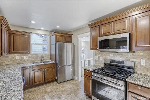 a kitchen with granite countertop a sink stove and refrigerator