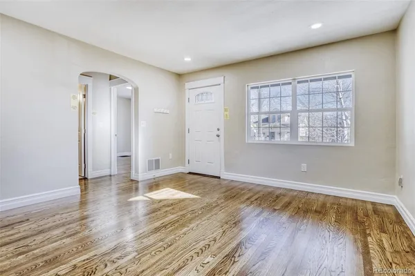 an empty room with wooden floor and windows