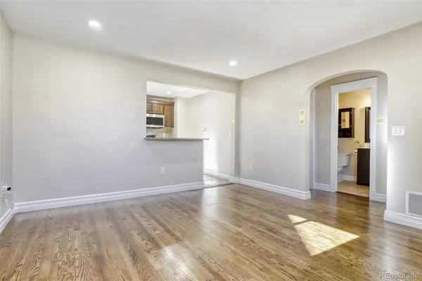 an empty room with wooden floor and windows