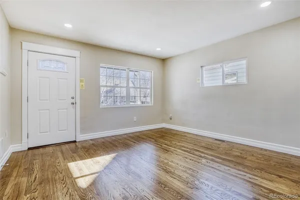 an empty room with wooden floor and windows